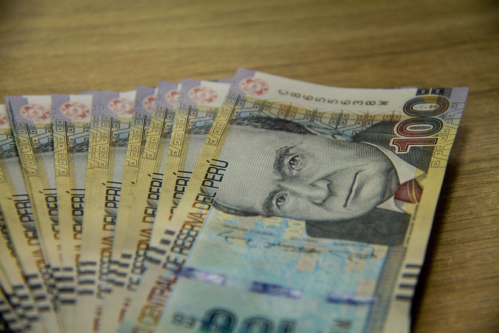 Peruvian soles banknotes and a travel card on a wooden table