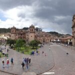 Travelers and locals around Cusco Plaza de Armas in a busy, well-lit tourist square