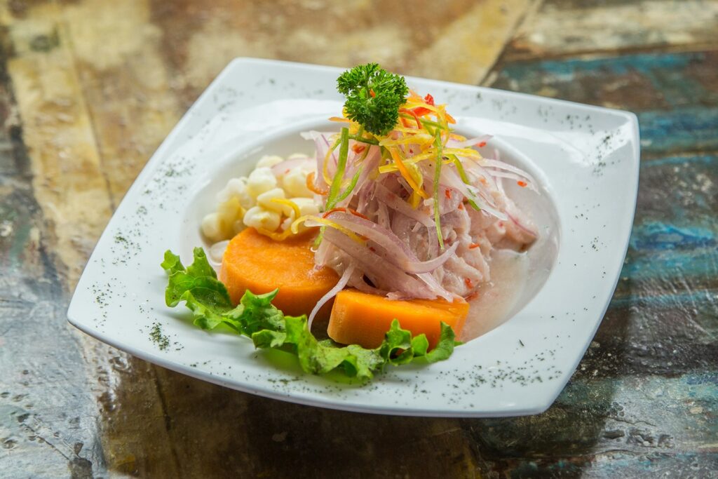 Fresh Peruvian cebiche with red onion and sweet potato on a simple white plate