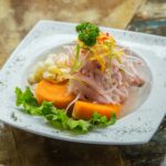 Fresh Peruvian cebiche with red onion and sweet potato on a simple white plate