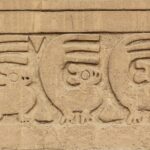 Chan Chan: carved earthen frieze with a row of repeated small animal figures and triangles on a sandy-colored adobe wall
