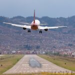 Passenger jet landing at Cusco airport with the city and Andean hills behind the runway