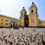 Yellow baroque Basilica and Convent of San Francisco in the Historic Centre of Lima, with pigeons in the plaza
