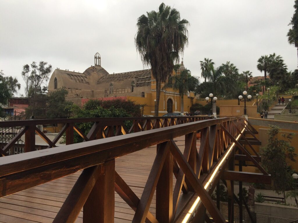 Puente de los Suspiros in Barranco, Lima, with wooden bridge, greenery and coastal neighborhood buildings