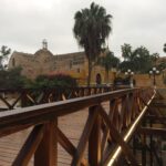 Puente de los Suspiros in Barranco, Lima, with wooden bridge, greenery and coastal neighborhood buildings