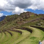 Sacred Valley day trip stop at Pisac: green Inca terraces curving around a hillside, with a footpath, hikers and mountains